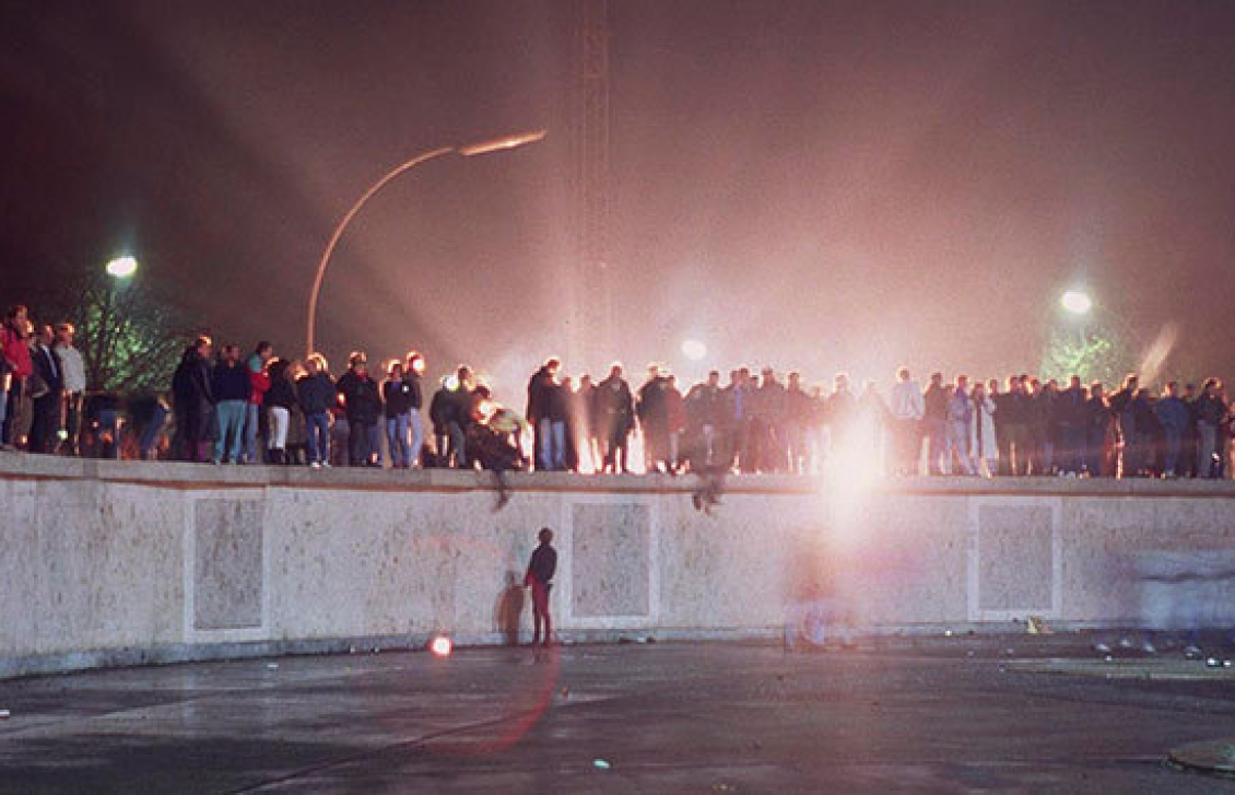 people standing on Berlin Wall at night